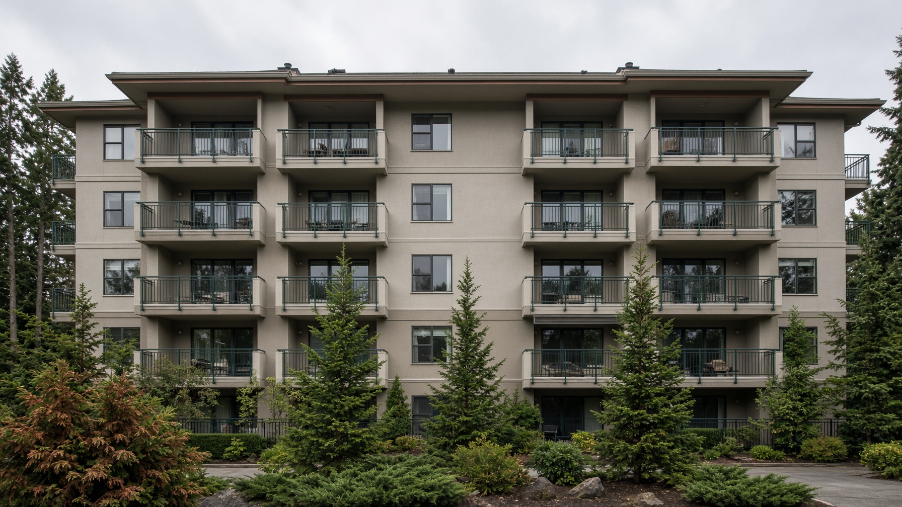 Freshly painted strata building with greige stucco and green balcony rails